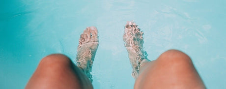 Ein Mensch streckt seine Füße ins Wasser