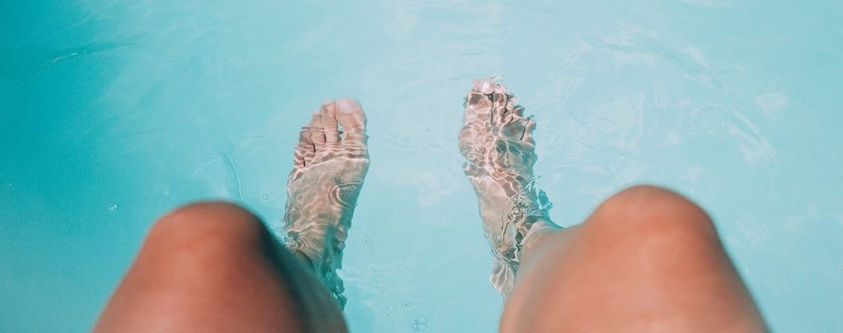 Ein Mensch streckt seine Füße ins Wasser